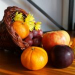 A vibrant cornucopia arrangement featuring apples, grapes, gourds, and flowers.
