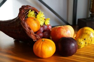 A vibrant cornucopia arrangement featuring apples, grapes, gourds, and flowers.